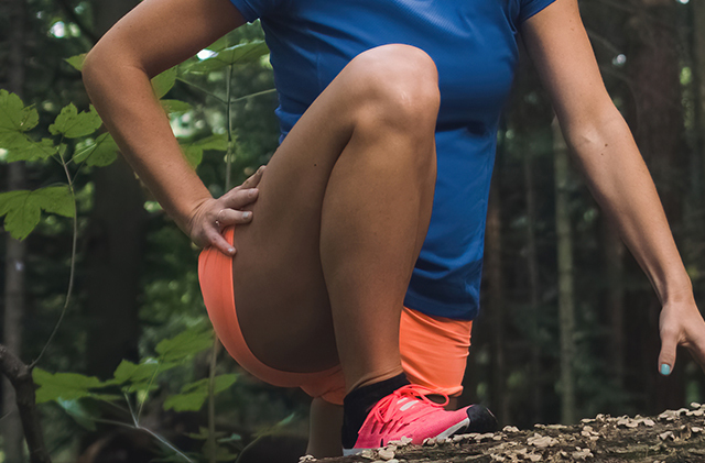 A woman wearing running attire stretches her leg.